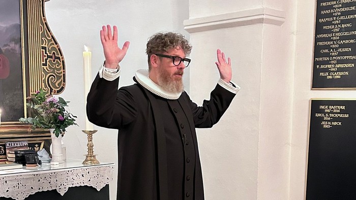 Mand i svart kapittel i kirke.