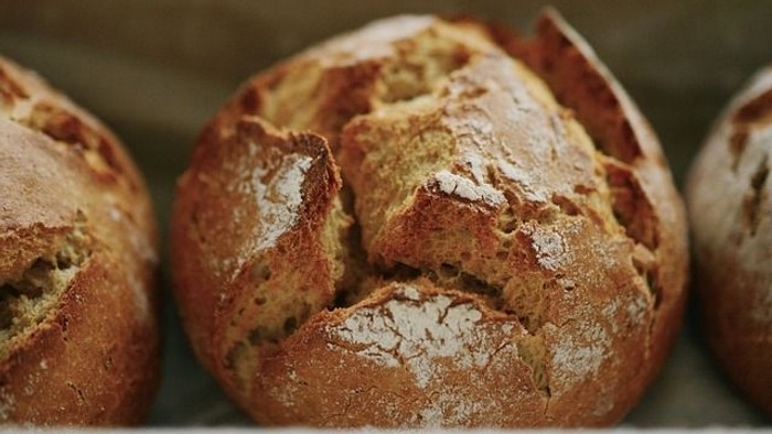 Drei frisch gebackene Brotlaibe auf einem Brett