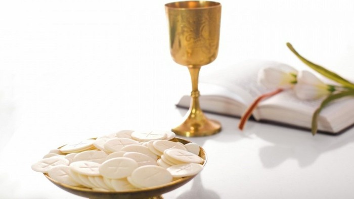 Goldener Kelch, Teller mit Oblaten und Buch auf weißem Tisch