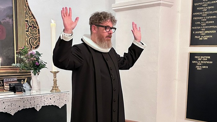 Mand i svart kapittel i kirke.