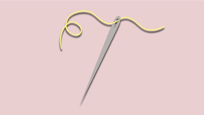 En nål med gult tråd.