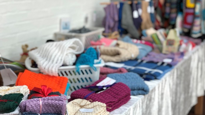 Bænken er dækket med forskellige farvede klæde og tøj, bl.a. skærp og skjorter.