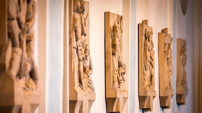 Aufwendig geschnitzte hölzerne Konsolen mit klassischen Menschendarstellungen an einer Galerie-Wand.