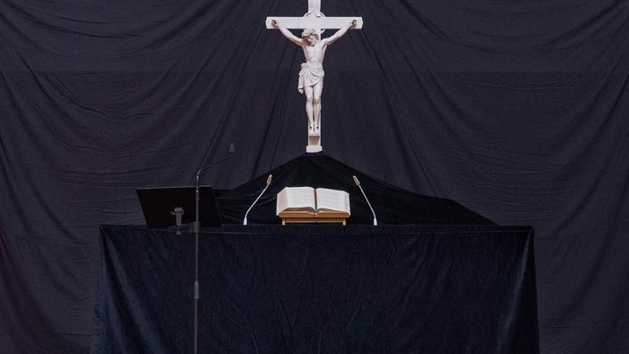 Ein Kruzifix steht auf einem schwarzen Tuch bedeckten Tisch mit einem Buch darunter