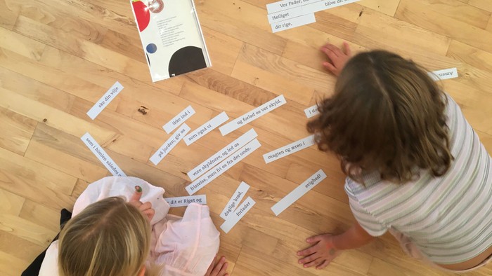 To børn sidder på gulv og læser papirklip.