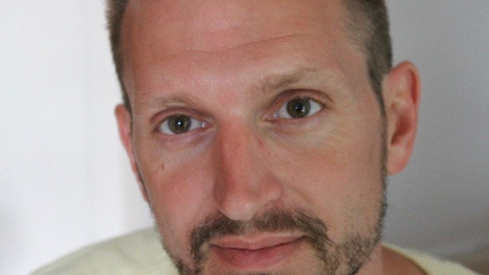 En mand med kort hår og skæg ser direkte i kameraet.