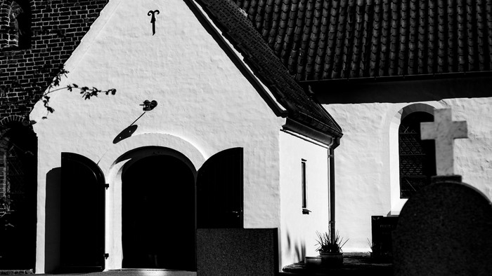 Sort-hvide billedet af en lille kirke med spids tak og to døre.