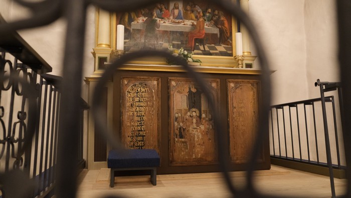 En altertavle i en kirke med malerier og skrift på en dør.