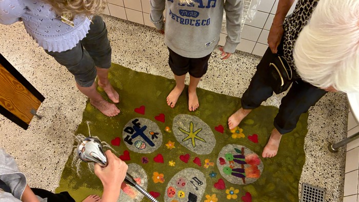 Børn, der står barfodede på en farverig sansesti-måtte med forskellige former og teksturer.