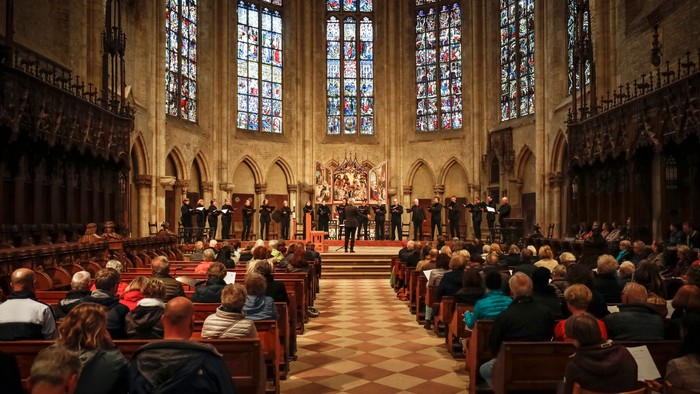 Große Kirche mit Menschen, die auf Bänken sitzen und einem Chor zuhören