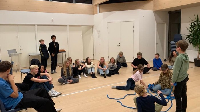 En gruppe mennesker, der deltager i en interaktiv workshop eller diskussion i et rummeligt indendørs lokale.