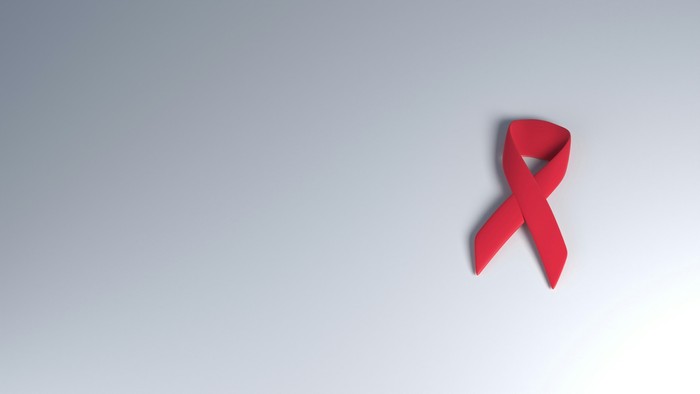 Eine leuchtend rote Schleife, die Bewusstsein und Unterstützung im Kampf gegen HIV/AIDS symbolisiert, vor einem hellblauen Hintergrund.