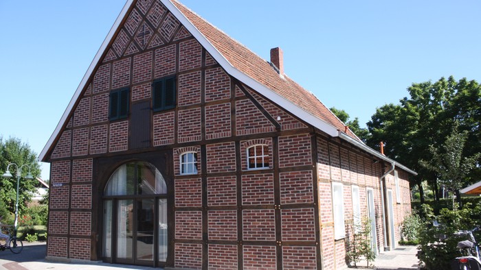 Das Bild zeigt ein traditionelles deutsches Haus mit einem steilen Dach und einem großen Torbogen.