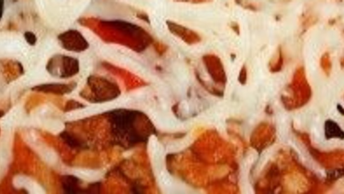 Ostet pastaret med strimlede nudler, hakket kød og ternede gulerødder på en gaffel.