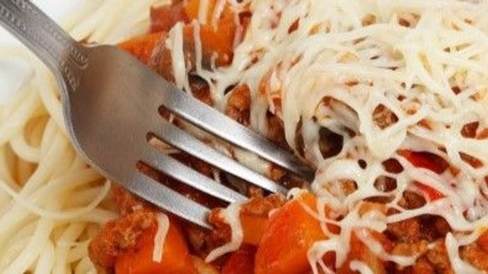 En gabel i en ret med pasta, tomatsoace og ost.