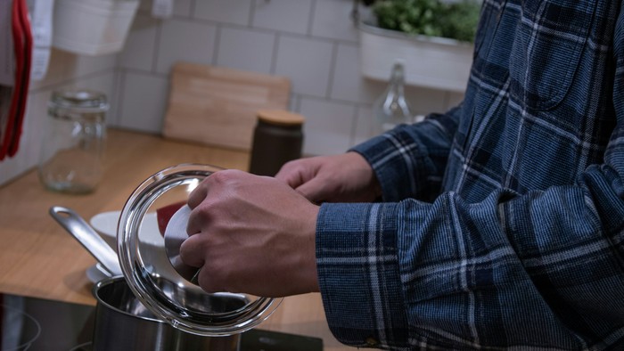 Das Bild zeigt Hände die in einem Kochtopf rühren.