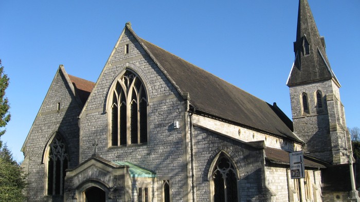 Stone church with tall steeple and arched windows.