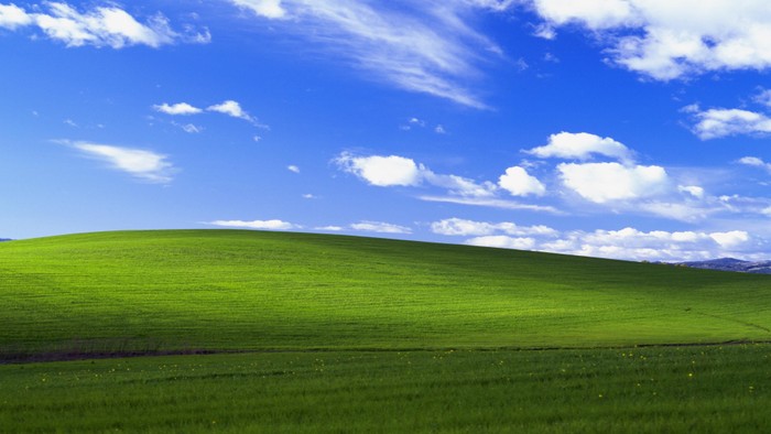Rolling green hills under blue sky with white clouds