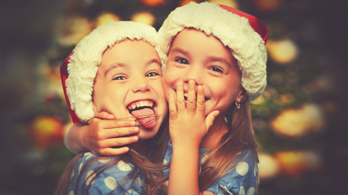 To børn i julestueklæder kigger forundret på noget.