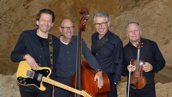 Band Cohan i kirken, 4 musiker står med guiter, cello og violin på sand