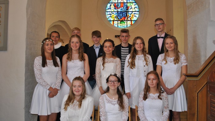 En gruppe børn og unge i hvidt tøj poserer i en kirke.