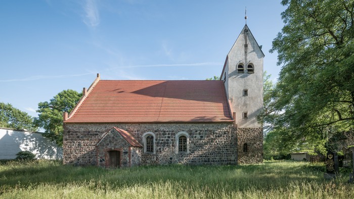 Kleine Kirche mit rotem Dach in ländlicher Umgebung