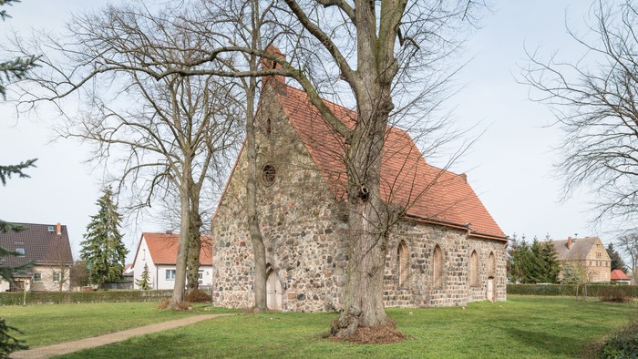Alte Kirche mit rotem Dach und Baum im Vordergrund
