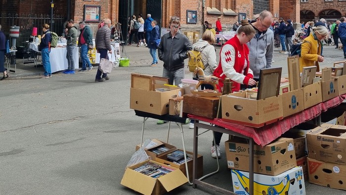 Freiluft-Flohmarktstand mit verschiedenen Artikeln zum Verkauf auf Pappkartons und Tischen.