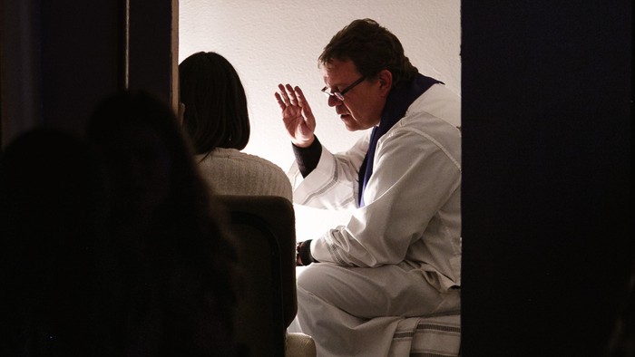 Ein Mann in weißem Anzug winkt auf einer Bühne.