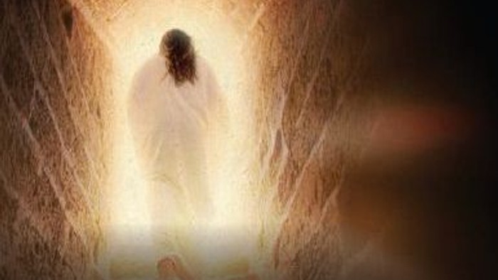 En lysende skikkelse træder frem fra indgangen til en glødende, æterisk grotte, omgivet af varmt lys.