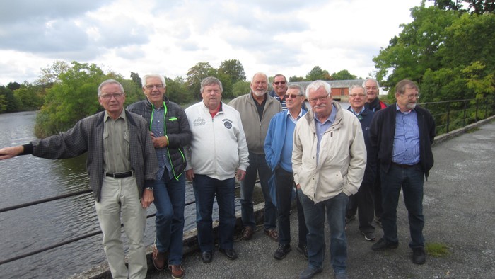 En gruppe mænd står sammen ved en sø