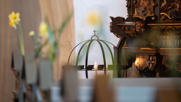 Elegant kirkealter med tændt lys, blomster og prangende religiøse dekorationer i blød fokus.