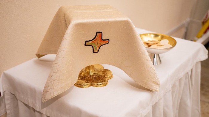 Elegante Tischdekoration mit kreuzbestickter Tischdecke, goldenen Tellern und einem Etagère-Ständer.