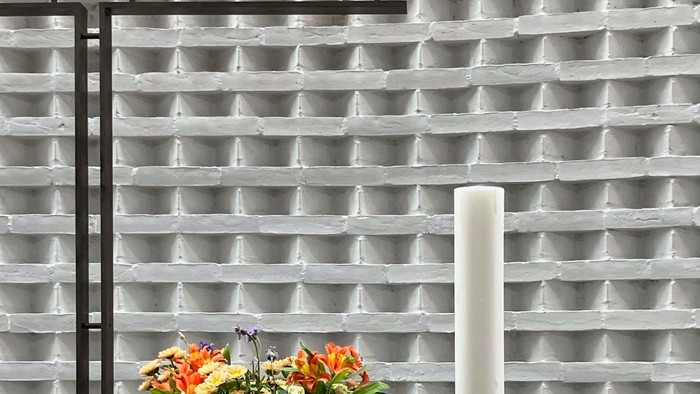 Blomster og lysestage på bord foran muret væg