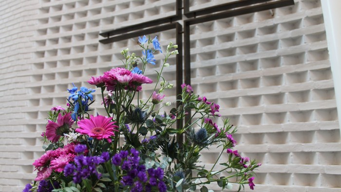Blomsterarrangement foran mur med kors
