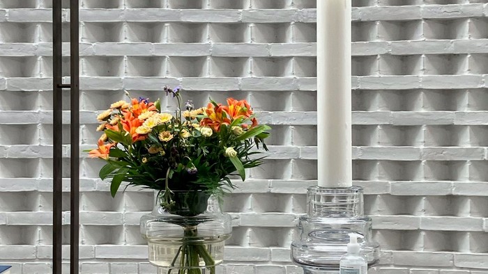 Blomster og lysestage på bord foran muret væg