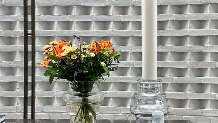 Blomster og lysestage på bord foran muret væg