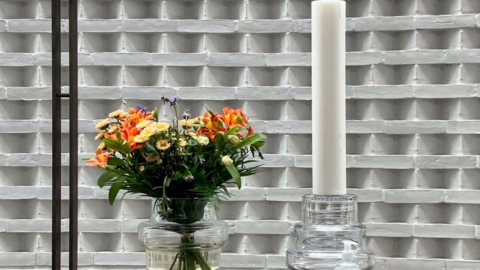 Blomster og lysestage på bord foran muret væg
