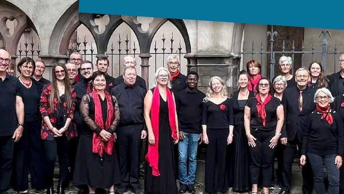 Groupe de personnes en chemises rouges assorties posant ensemble devant une arche en pierre ornée.