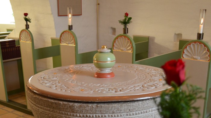 En smukk, hvid keramisk fontæne med udsmykning og en blomst i den.