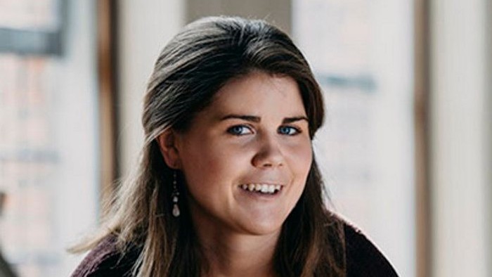 En kvinde med langt mørkt hår smiler til kameraet.