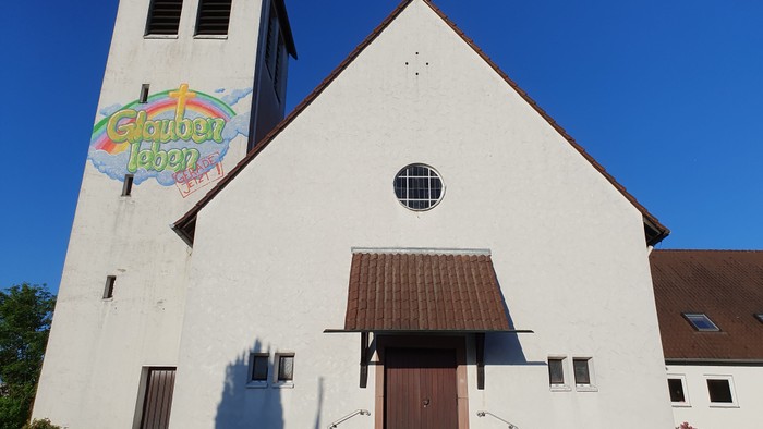 Weiße Kirche mit buntem Schild, klarer blauer Himmel