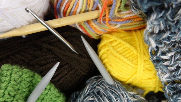Bunte Wolle, Stricknadeln und fertige Strickstücke