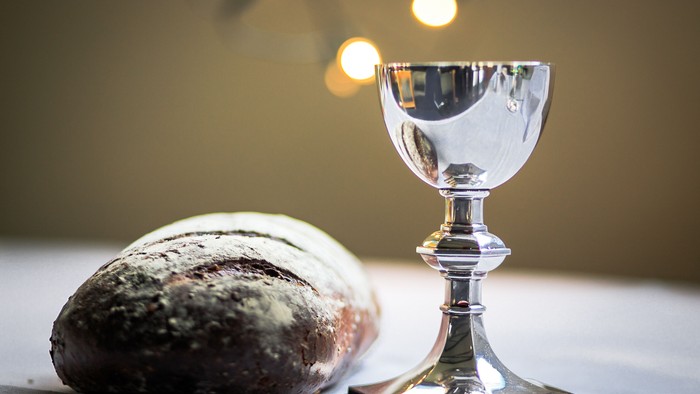 Silver chalice next to loaf of bread