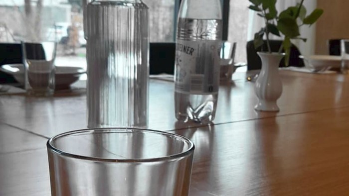 Ein Tisch mit Gläsern, Blumen und Besteck, davor ein Teller