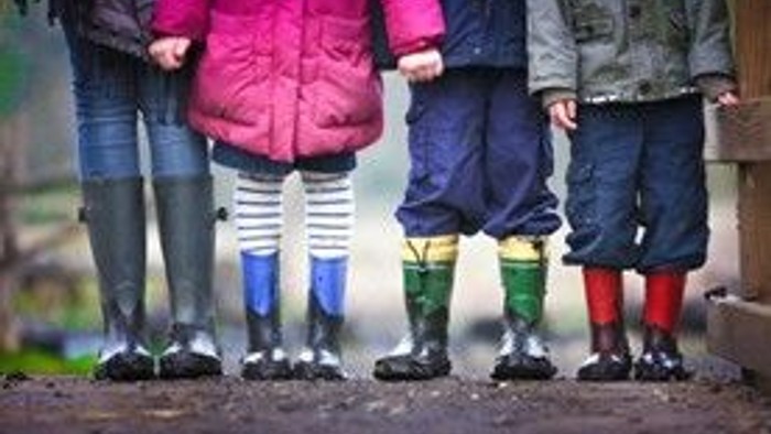 Vier Kinder in bunten Socken stehen im Matsch.