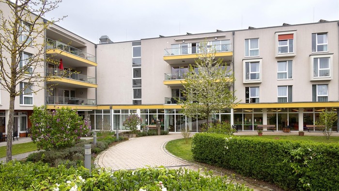 Moderner Wohnkomplex mit begrüntem Innenhof, der Grünflächen, Gehwege und Balkone umfasst.