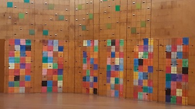 Farbenfrohe Kunstinstallation mit quadratischen Paneelen an Holzwänden