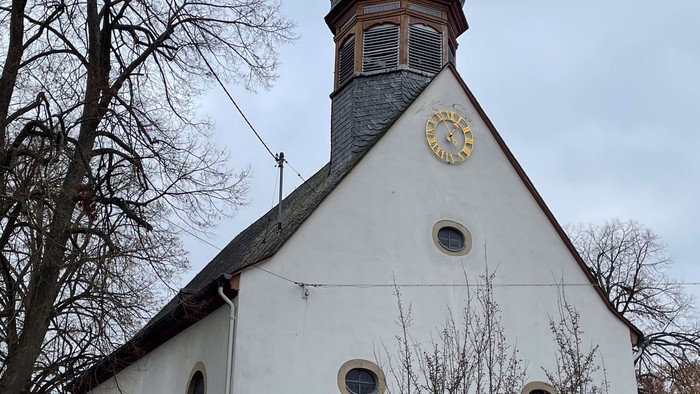 Weiße Kirche mit hohem Turm und Uhr.