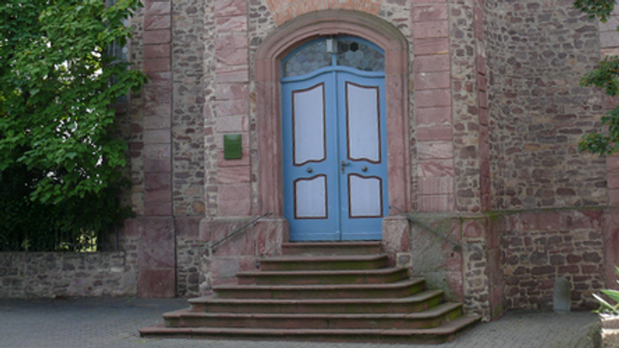 Historischer Ziegelsteingebäude-Eingang mit blauen Doppeltüren und steinernen Stufen.
